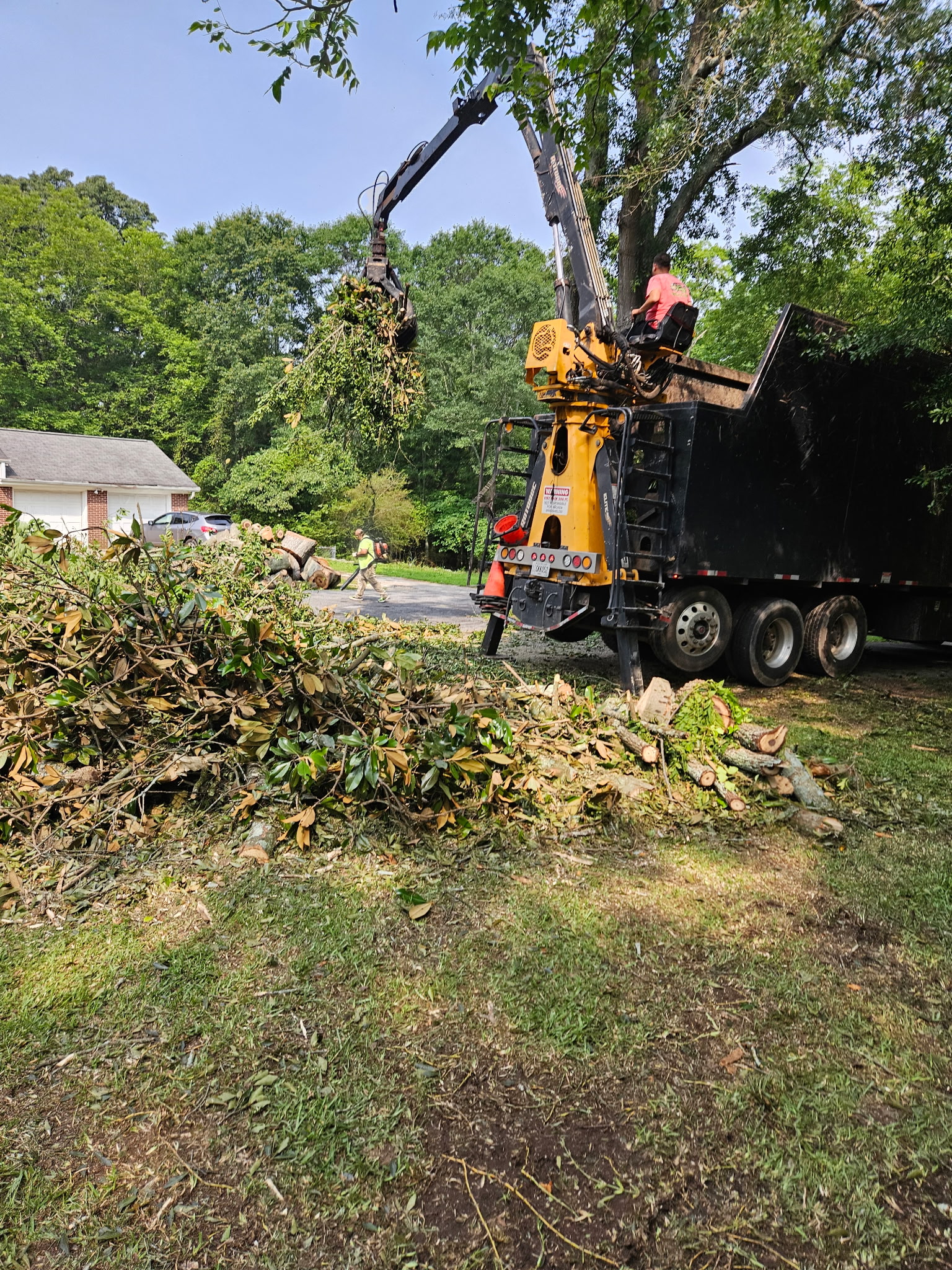 Grapple truck loading branches during residential tree removal